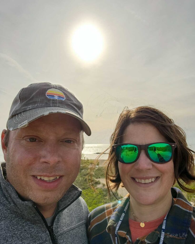 Kyle + Kara selfie with sun and New Buffalo harbor in background